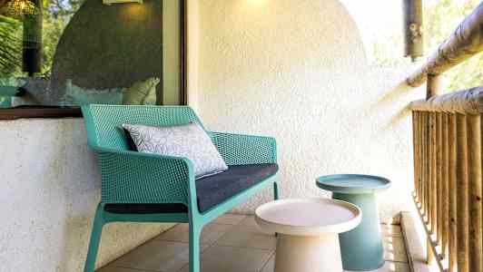 Terrasse med en grønn stol og små bord. (AI-generert tekst)