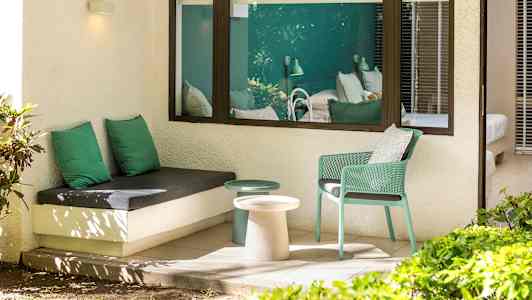 Utendørs sitteområde med grønt interiør og utsikt mot soveromsinteriør. (AI-generert tekst)