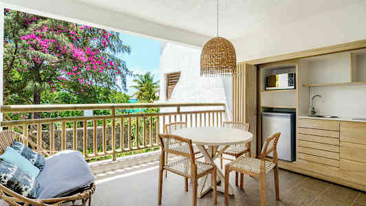 En terrasse med bord og stoler, samt utsikt mot grønnsaker og blomster. (AI-generert tekst)