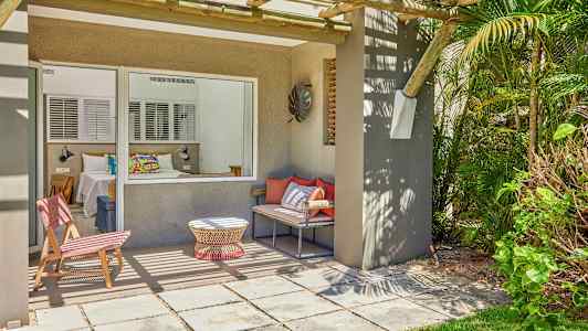 En terrasse med sitteplasser og utsikt mot et soverom gjennom et stort vindu. (AI-generert tekst)