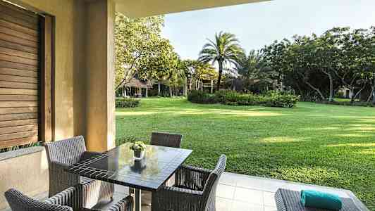 Uteområde med bord og stoler, utsikt over en frodig hage. (AI-generert tekst)