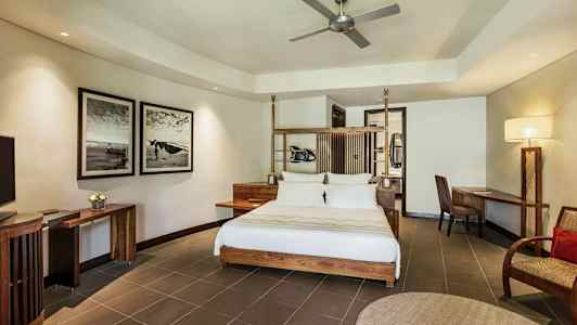 Moderne innredet hotellrom med dobbeltseng, skrivebord og stol, veggkunst og takvifte. (AI-generert tekst)