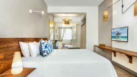 Bilde av et moderne hotellrom med tremøbler, seng med hvite laken og fargerike puter, og et stort vindu i bakgrunnen. (AI-generert tekst)