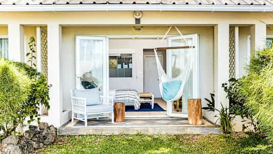 Bilde av en terrasse med åpen terrassedør, en hvit sittegruppe, en hengekøye og grønne planter rundt omkring. (AI-generert tekst)