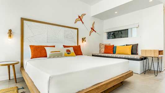 Moderne hotellrom med dobbeltseng og fargerike puter. (AI-generert tekst)