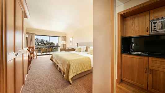 Bilde av et hotellrom med en seng og et trekjøkken. (AI-generert tekst)