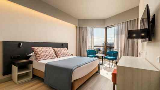 Moderne hotellrom med dobbeltseng, sittegruppe og utsikt. (AI-generert tekst)