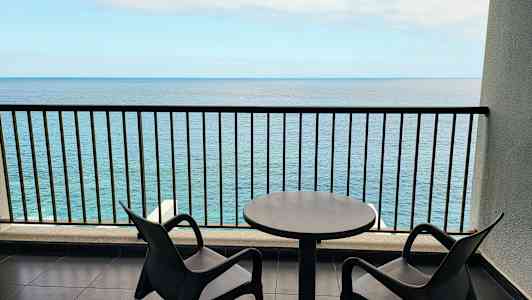 To stoler og et bord på en balkong med havutsikt. (AI-generert tekst)