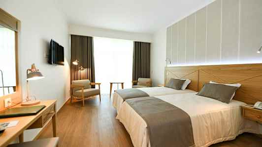 Hotellrom med to enkeltsenger, skrivebord og sitteplasser. (AI-generert tekst)