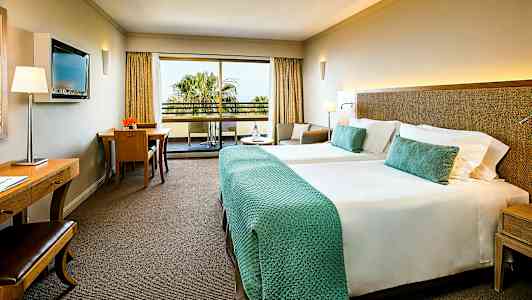 Hotellrom med to senger og balkong. (AI-generert tekst)