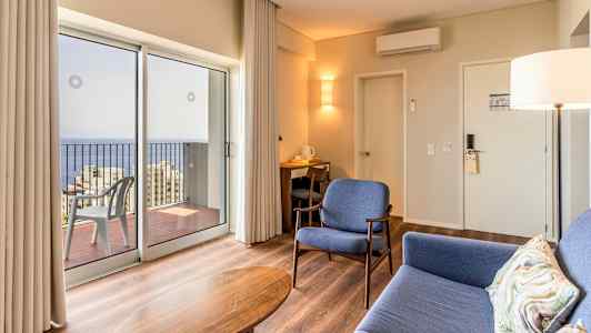 Moderne hotellrom med sitteplasser og utsikt over havet gjennom store vinduer. (AI-generert tekst)