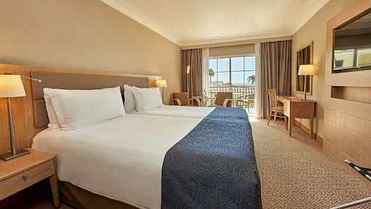 Hotellrom med to enkeltsenger og en balkong med utsikt. (AI-generert tekst)