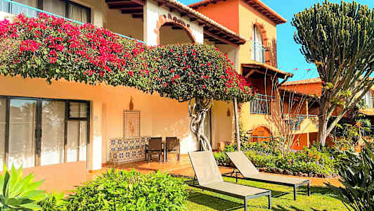 En bygning med blomsterdekorasjoner, grøntområder og solsenger på en gressplen. (AI-generert tekst)