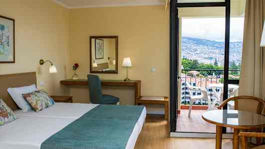 Hotellrom med dobbeltseng, skrivebord og balkong med utsikt. (AI-generert tekst)