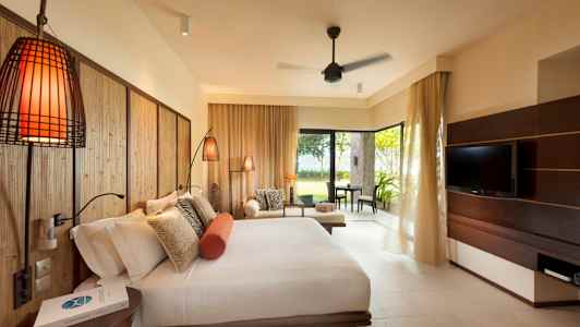 Et hotellrom med en stor seng, en sittegruppe og en TV, samt utsikt mot en frodig hage. (AI-generert tekst)