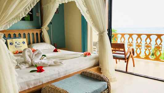 Et soverom med utsikt over havet, dekorert med blomster på sengen. (AI-generert tekst)