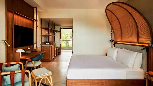 Et moderne hotellrom med en seng, et skrivebord og en sittegruppe. (AI-generert tekst)