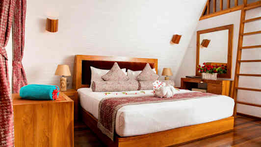 Et stilrent soverom med en dobbeltseng, tredetaljer og dekorerte puter. (AI-generert tekst)