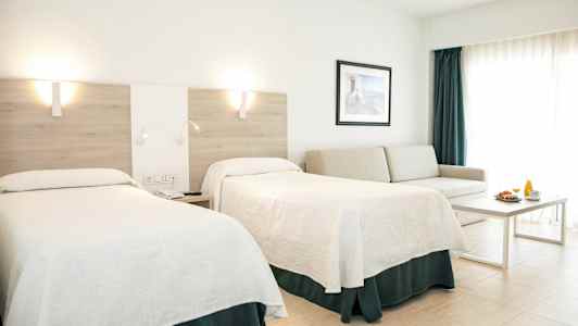 Et hotellrom med to senger, en sofa, et bord og en frokostservering. (AI-generert tekst)