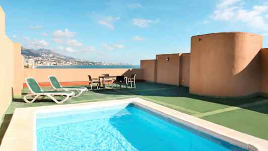 En terrasse med basseng, solsenger og utsikt over havet. (AI-generert tekst)