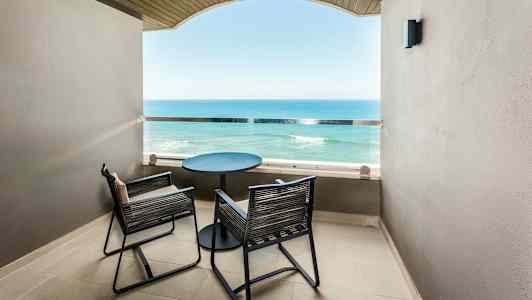 En balkong med to stoler og et bord med utsikt over havet. (AI-generert tekst)