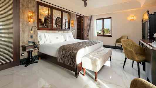 Et hotellrom med en stor seng, sittemøbler og et skrivebord. (AI-generert tekst)