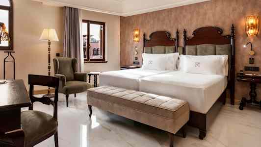 Rom med to senger, en sitteplass og vinduer. (AI-generert tekst)