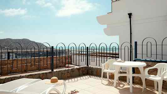 Terrasse med solsenger, bord og stoler, havutsikt. (AI-generert tekst)