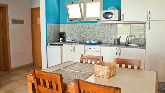 Et kjøkken med et bord og fire trestoler. (AI-generert tekst)