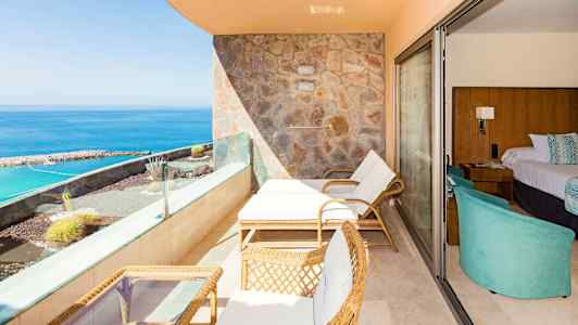 En terrasse med solsenger, bord og havutsikt, ved siden av et hotellrom. (AI-generert tekst)