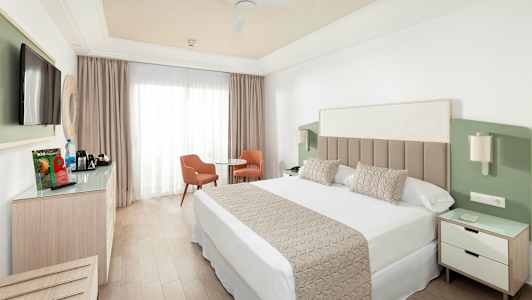 Hotellrom med dobbeltseng, TV, sittegruppe og garderobe. (AI-generert tekst)