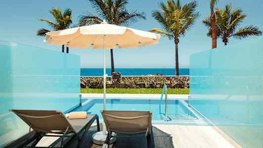 Bilde av to solsenger og en parasoll ved et privat basseng med utsikt mot havet. (AI-generert tekst)