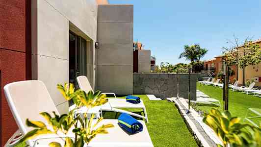 Solstoler med blå håndklær på en gressplen nær et hus. (AI-generert tekst)