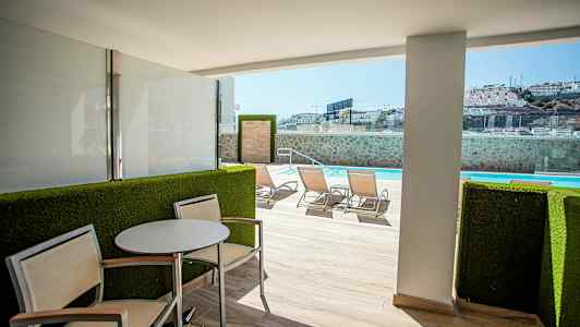 Utendørsterrasse med sitteområde og utsikt mot svømmebasseng. (AI-generert tekst)