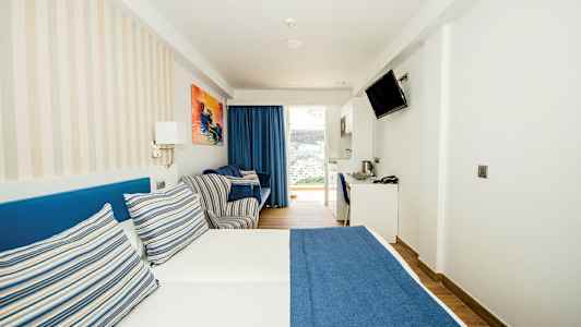 Et hotellrom med en dobbeltseng med blått sengetrekk og stripete puter. (AI-generert tekst)