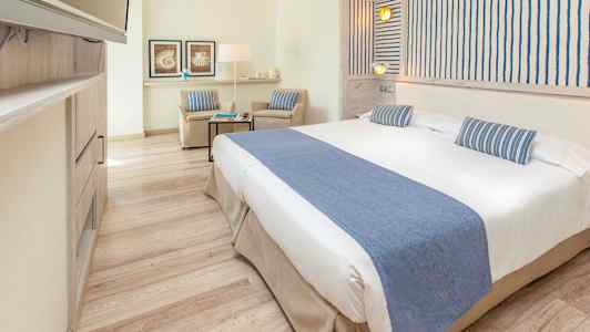 Et lyst hotellrom med en bred seng og blå dekorasjoner. (AI-generert tekst)