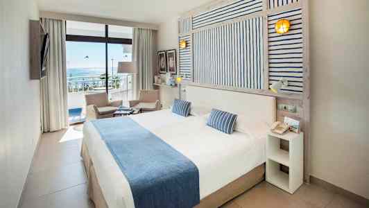 Dobbeltrom med havutsikt, møbler i lyse farger. (AI-generert tekst)