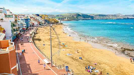 Strand med mennesker, sjø og gangvei. (AI-generert tekst)