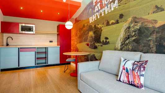 Et moderne kjøkken med sittegruppe og sofa ved en vegg med naturmotiv. (AI-generert tekst)