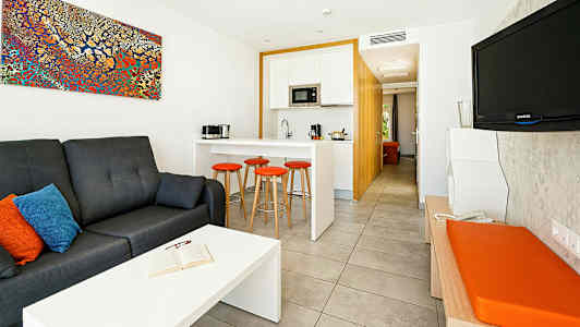 Et moderne hotellrom med en sittegruppe, kjøkken og TV. (AI-generert tekst)