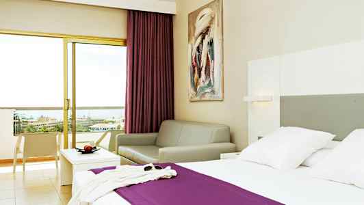 Hotellrom med en seng, en sofa og en balkong med utsikt. (AI-generert tekst)