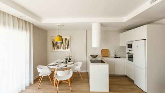 Moderne kjøkken med spiseplass, hvite møbler og lys innredning. (AI-generert tekst)