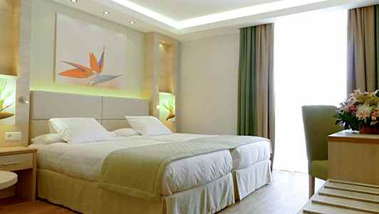 Hotellrom med en dobbeltseng, dekorasjoner og et vindu med gardiner. (AI-generert tekst)