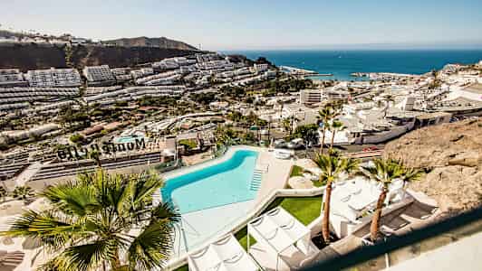 Utsikt over en ferieby ved kysten med basseng og bygninger. (AI-generert tekst)