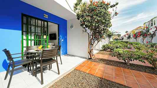 Terrasse med bord og stoler, omgitt av planter og blomster. (AI-generert tekst)