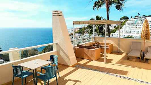 Terrasse med havutsikt, sittemøbler og solsenger. (AI-generert tekst)