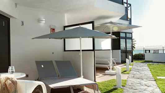 Utendørsvisning med to solsenger og parasoller ved en bygning. (AI-generert tekst)