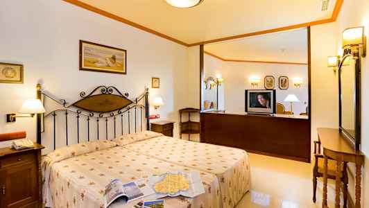 Et hotellrom med en dobbeltseng, nattbord og en TV på en møbel. (AI-generert tekst)