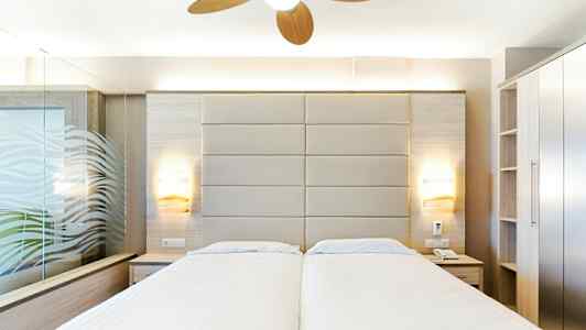 Hotellrom med to enkeltsenger, moderne innredning og takvifte. (AI-generert tekst)