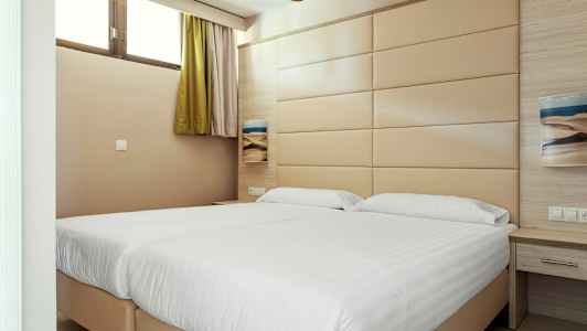 Et hotellrom med to senger og en beige veggpanel. (AI-generert tekst)